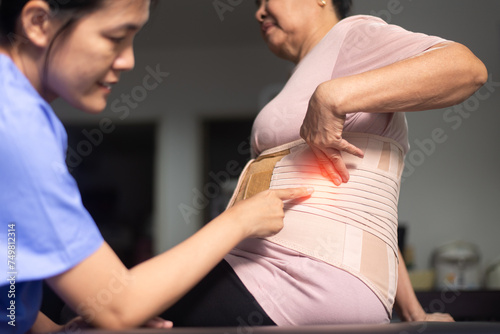 Physiotherapist checking senior women patient orthopedic corset at clinic