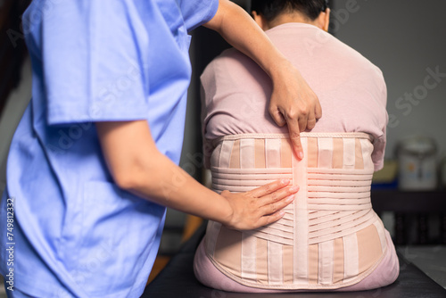 Physiotherapist treat senior women patient orthopedic corset at clinic photo