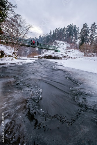 Half-frozen Hornad river with rapids in winter at sunset Slovak Paradise. An iron bridge over a frozen river. Discovering the beauty of the winter landscape. photo