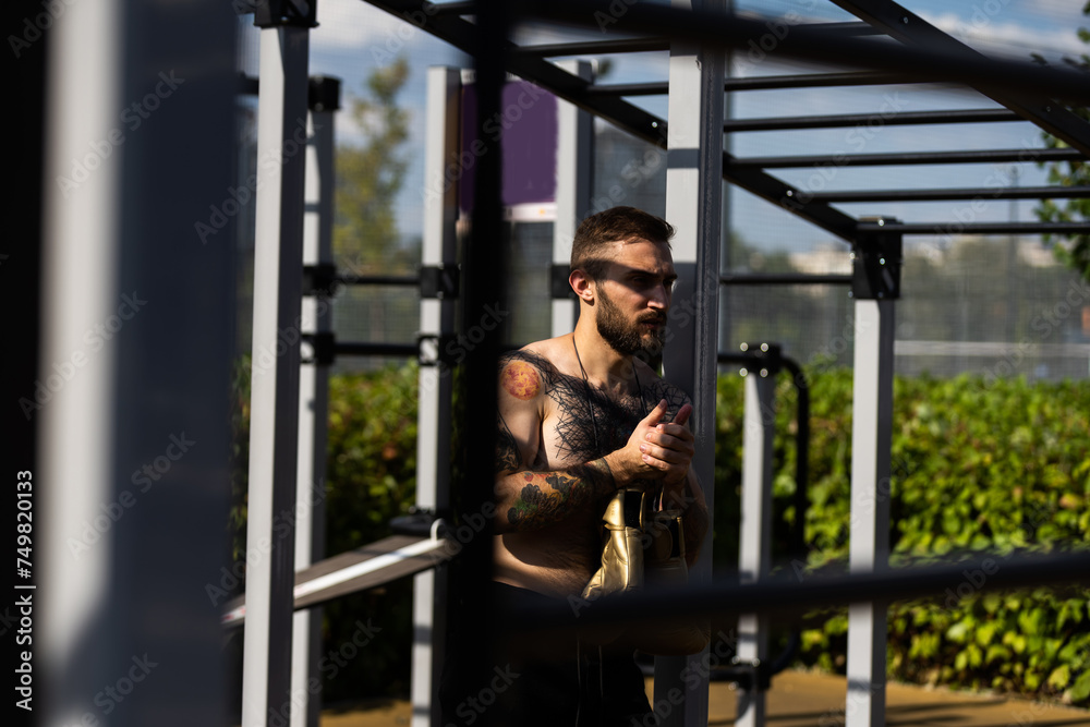 Man in boxing gloves is practicing on an outdoor sports field