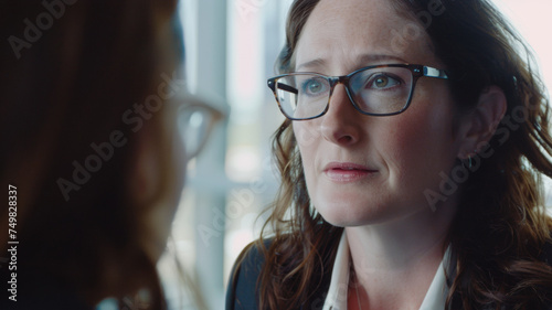 A concerned woman listens intently, her furrowed brow reflecting the gravity of the conversation.