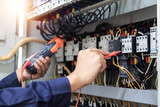 Electrician engineer work tester measuring voltage and current of power electric line in electical cabinet control , concept check the operation of the electrical system . 