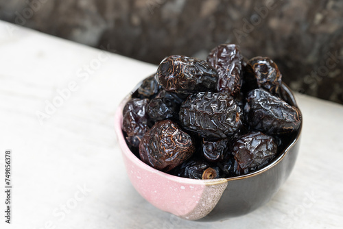 Ajwah dates in a ceramic bowl on a white wooden background are the best fruits of Medina. photo