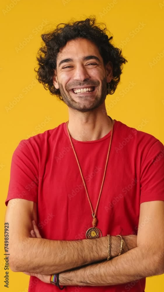 Smiling man crossing his arms and looking at camera isolated on yellow background in studio Smiling man crossing his arms and looking at camera isolated on yellow background in studio