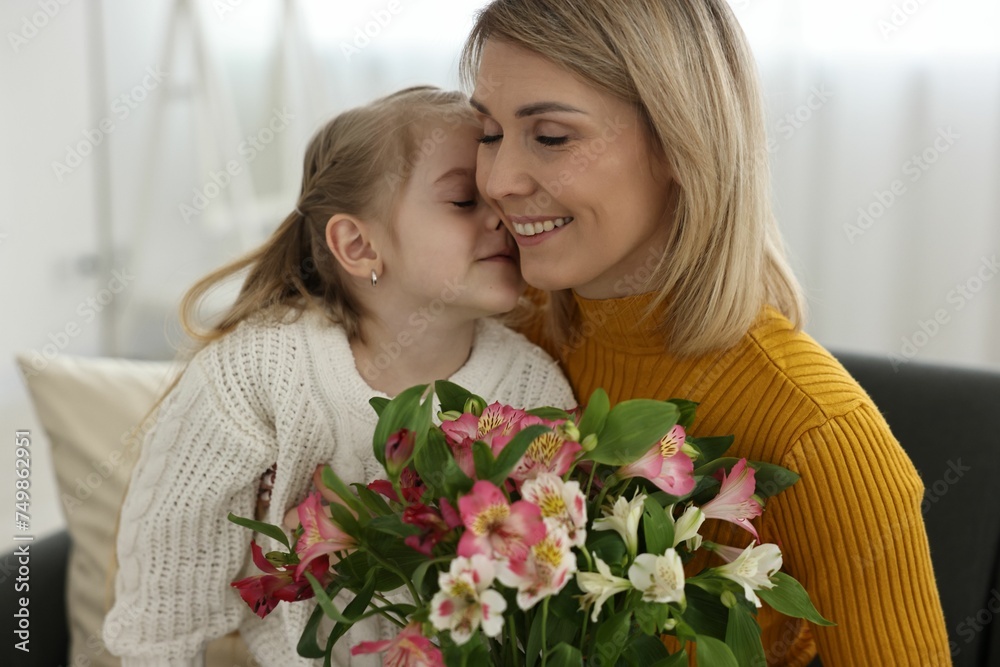 Little daughter kissing and congratulating her mom with bouquet of alstroemeria flowers at home. Happy Mother's Day Little daughter kissing and congratulating her mom with bouquet of alstroemeria flowers at home. Happy Mother's Day