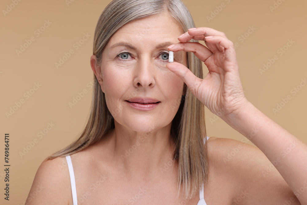 Beautiful woman with vitamin capsule on beige background Beautiful woman with vitamin capsule on beige background