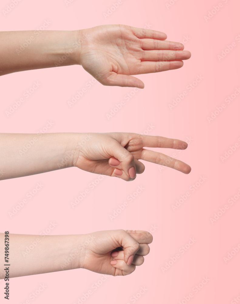 People playing rock, paper and scissors on pink background, closeup