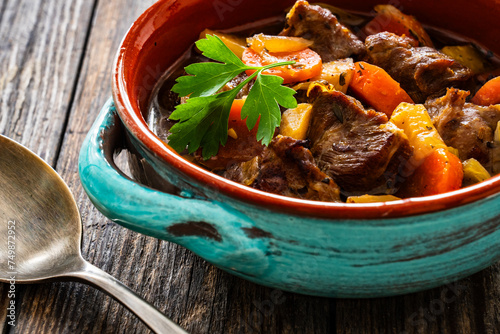 Roast pork cheeks with carrots and celeriac in sauce on wooden table
 photo