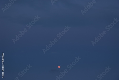 氷霧で覆われた日没後の田園地帯で見かけた赤く染まる満月