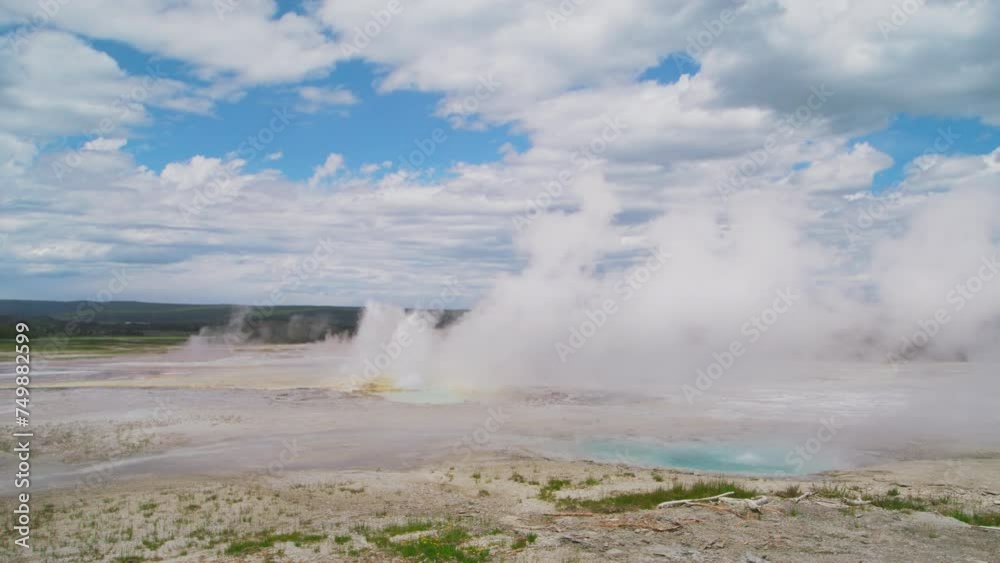 A wide-angle view of Yellowstone's geyser basin showcases a vast, open landscape under a dramatic sky filled with fluffy clouds, conveying a sense of openness and wonder. Slow Motion, 4K RAW. A wide-angle view of Yellowstone's geyser basin showcases a vast, open landscape under a dramatic sky filled with fluffy clouds, conveying a sense of openness and wonder. Slow Motion, 4K RAW.