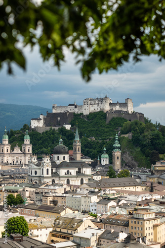 An early summer cloudy day in the historic centre of Salzburg in Austria framed with green leaves of a tree