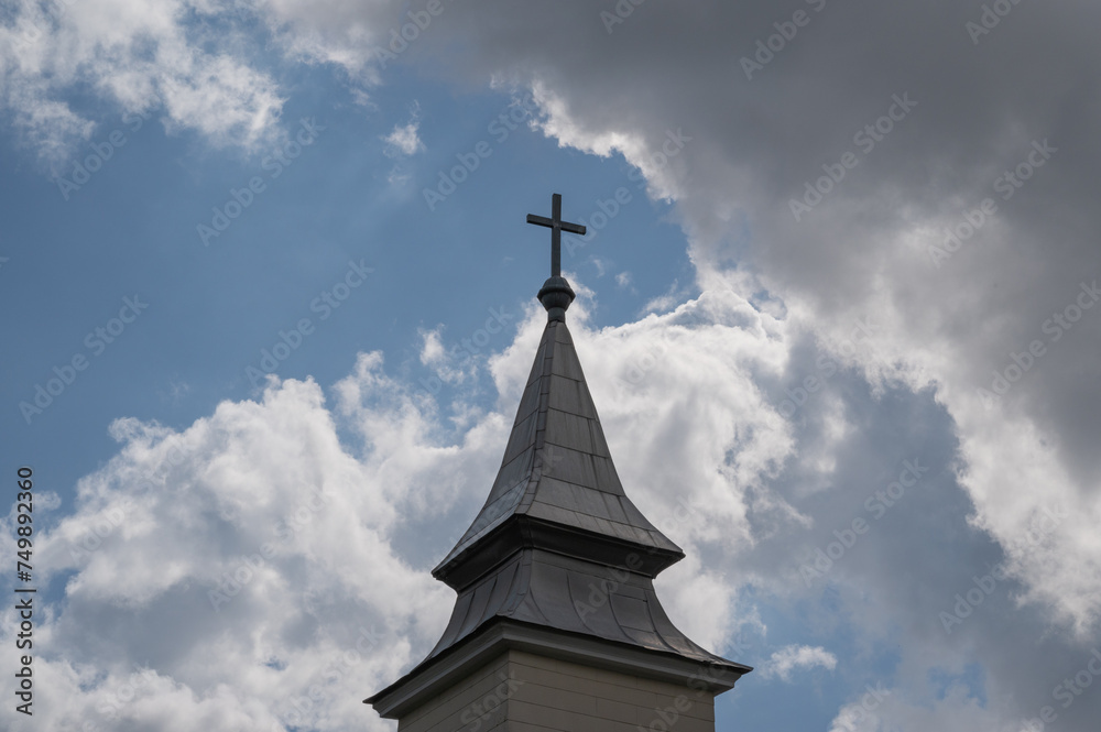 cross on the bell tower or dome of an old church against a background of clouds in europe
