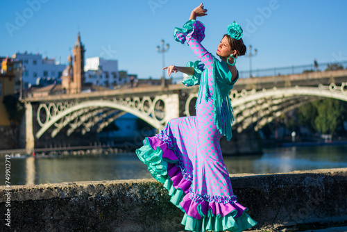 the girl with the flamenco dress in front of the Triana bridge and the Guadalquivir river in the center of Seville, Andalusia
