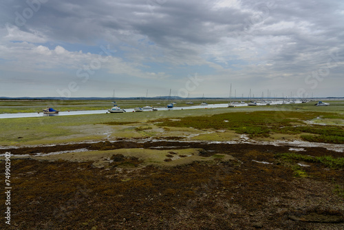 Dark clouds over Mengham Salterns on Hayling Island at low tide on a summer morning.