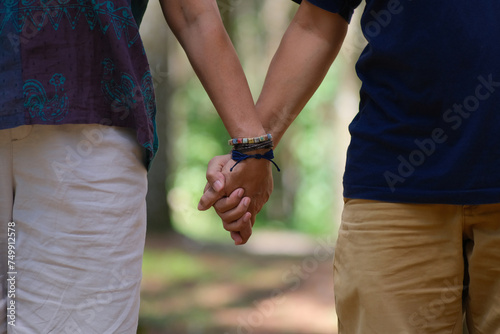 Closeup shot of a man and woman holding hands while walking in the park