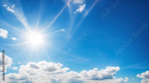 Glowing sun rays filtering through a partly cloudy clear blue sky 
