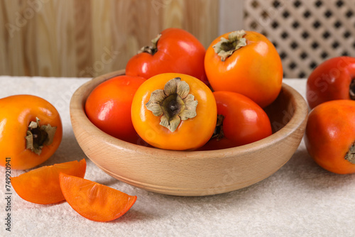 Delicious ripe persimmons on light textured table indoors, closeup