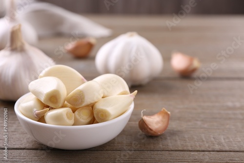 Aromatic garlic cloves and bulbs on wooden table, closeup. Space for text