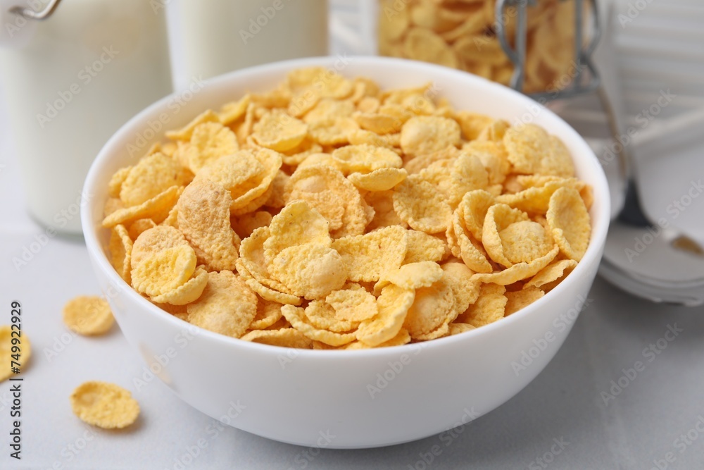 Tasty crispy corn flakes in bowl on white table, closeup. Breakfast cereal Tasty crispy corn flakes in bowl on white table, closeup. Breakfast cereal