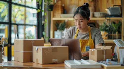 Startup SME small business entrepreneur of freelance Asian woman using a laptop with box Cheerful success Asian woman her hand lifts up online marketing packaging box and delivery SME idea