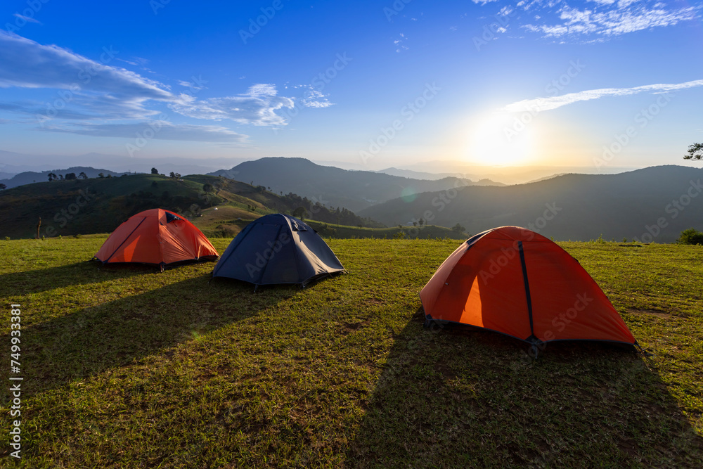 Group of adventurer tents during overnight camping site at the beautiful scenic sunset view point over layer of mountain for outdoor adventure vacation travel