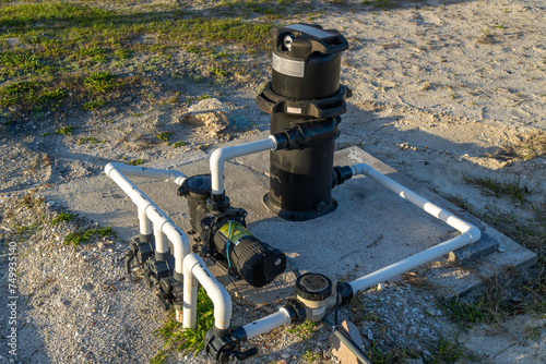 Pool equipment on a cement pad in sandy soil, filter, pump, valve, chlorinator photo