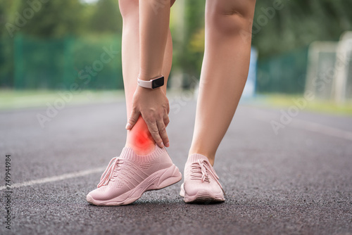 Achilles tendon injury, callus on the heel while running, foot pain, woman suffering from feet ache on a sports ground, podiatry concept photo