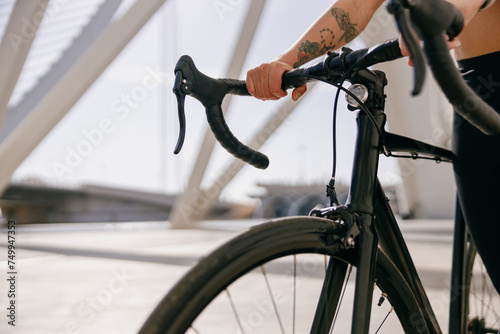 Close up of woman cyclist standing with her bike while training outdoors 