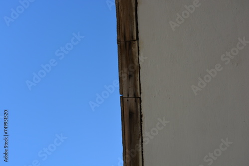Dark blue sky with white clouds, the top of a tree, a white cement roof and a wooden beam. photo