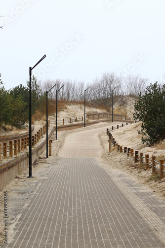 modern pathway to the beach with street lights and wooden fence