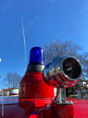 Obraz na płótnie Vintage siren, antenna, and a blue rotating beacon on the roof of a red ambulance from the Santo Tirso Volunteer Firefighters on exhibition at Sao Bento Count Square in Portugal. w salonie