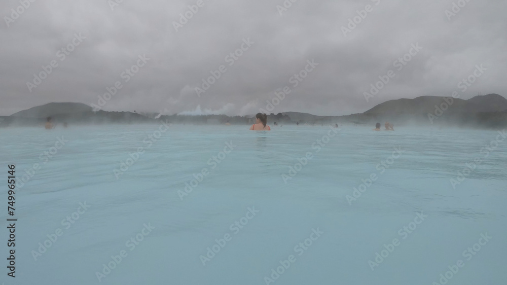 The Blue Lagoon geothermal spa Iceland, in a lava field near Grindavík on Reykjanes Peninsula. Water's milky blue shade is due to its high silica content. Woman relaxes and enjoy of spa in hot spring.
