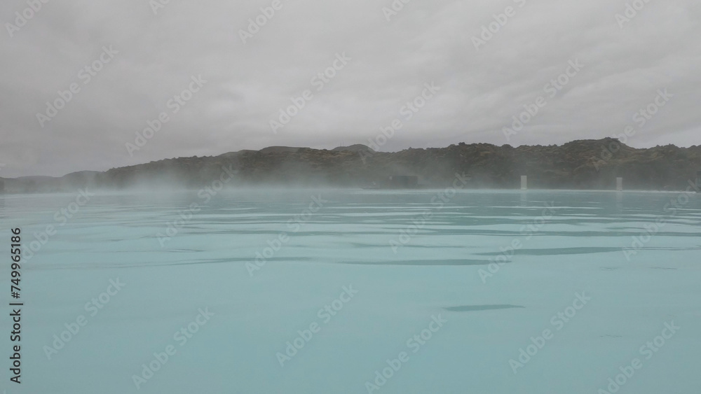 The Blue Lagoon geothermal spa Iceland, in a lava field near Grindavík on Reykjanes Peninsula. Water's milky blue shade is due to its high silica content. Woman relaxes and enjoy of spa in hot spring.