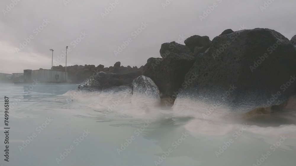 The Blue Lagoon geothermal spa Iceland, in a lava field near Grindavík on Reykjanes Peninsula. Water's milky blue shade is due to its high silica content. Woman relaxes and enjoy of spa in hot spring.