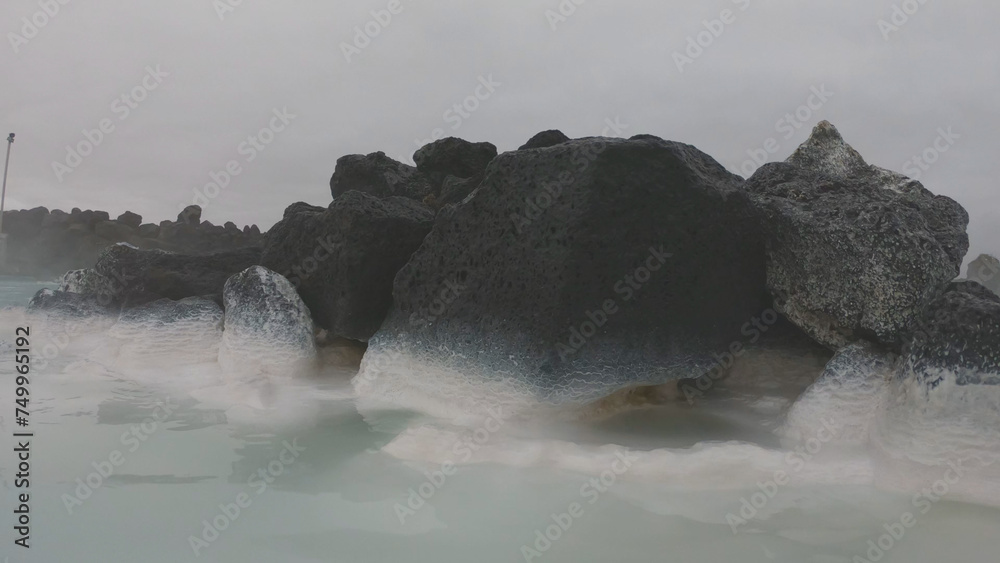 The Blue Lagoon geothermal spa Iceland, in a lava field near Grindavík on Reykjanes Peninsula. Water's milky blue shade is due to its high silica content. Woman relaxes and enjoy of spa in hot spring.