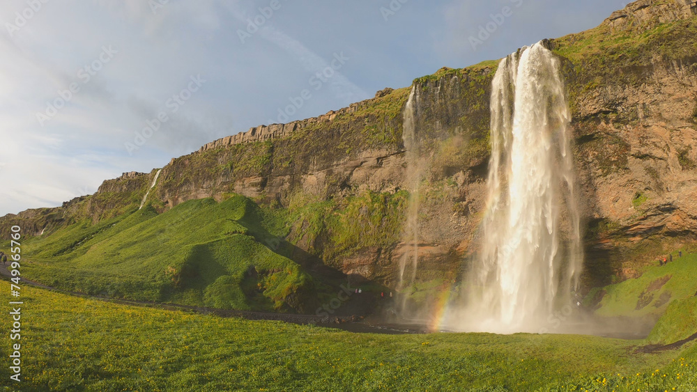 The Seljalandsfoss waterfall on the south coast of Iceland bathed in the otherworldly light of the midnight sun. The waterfall drops 60 meters and is part of the Seljalands River.