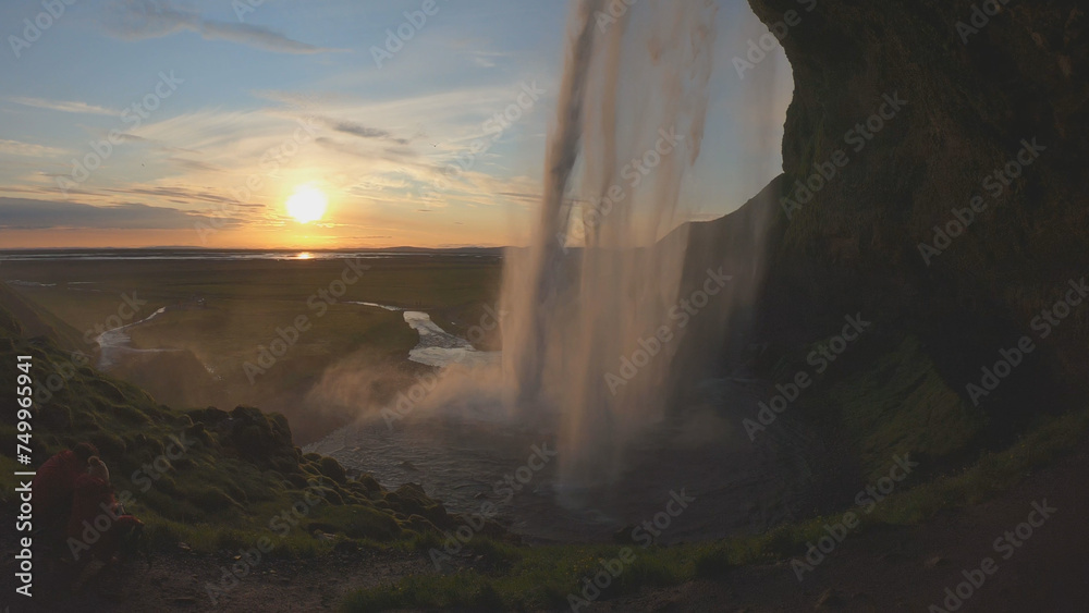 The Seljalandsfoss waterfall on the south coast of Iceland bathed in the otherworldly light of the midnight sun. The waterfall drops 60 meters and is part of the Seljalands River.