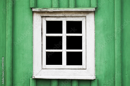 Rustic window in wooden village cottage house. Green wood wall. Countryside architecture background. Small window frame white paint. Empty copy space interior. Square shape window.
