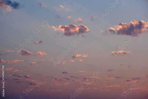 Sunset with pink and orange clouds in the sky, as the sun's rays gently pass through them in the evening.