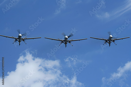 Three military drones flying in the blue sky