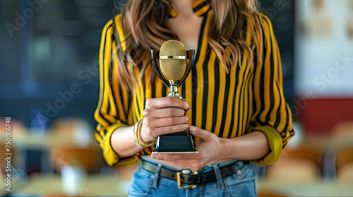 Up-close view of a woman’s torso as she grips a golden microphone trophy, suggesting a celebration of musical or vocal achievement