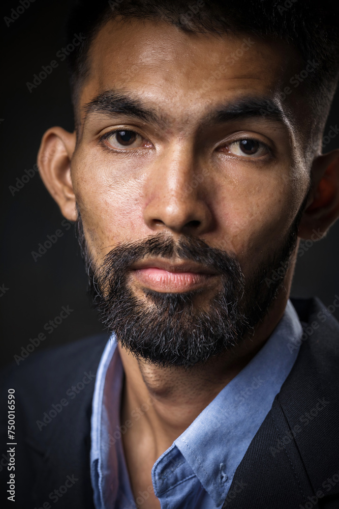 Obraz premium Close-up of young man's face with a beard and mustache in a black studio, background.