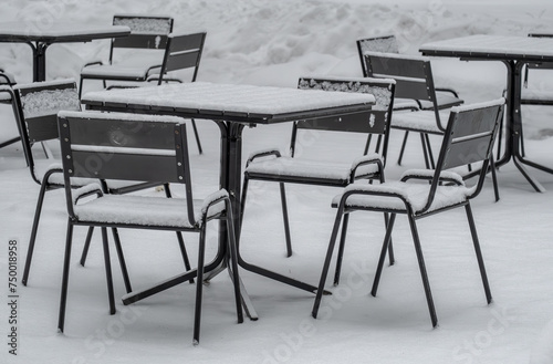 A table and chairs under the snow in winter outside.