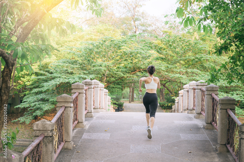 Fototapeta premium asian woman jogger, running over the bridge in public park.