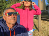 Father and daughter looking at the sun during a solar eclipse on a country park, family outdoor activity