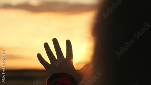Children prayer. Boy stretches his hand to beautiful sky, dreams in nature. Hand of child boy stretches to beautiful sky, sunset. Children dreams hopes, reach out your hands to sky. Child is playing photo