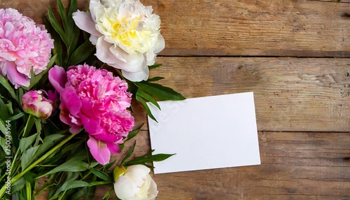Mock up of blank white paper card and beautiful peonies on wooden table.