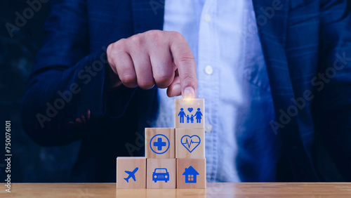 Businessman hand choose wooden blocks with icons of various types of insurance, protection icons for safety family insurance. Life insurance concept.