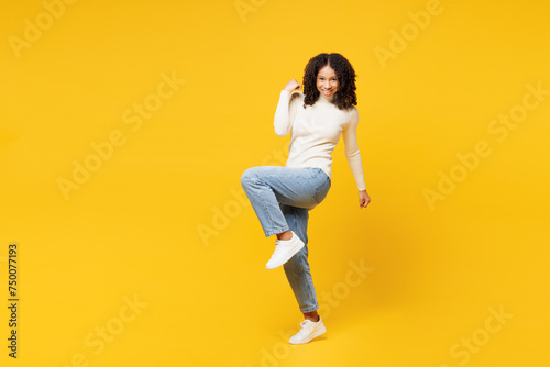 Fototapeta Naklejka Na Ścianę i Meble -  Full body little kid teen girl of African American ethnicity wear white casual clothes doing winner gesture celebrate clenching fists isolated on plain yellow background. Childhood lifestyle concept.