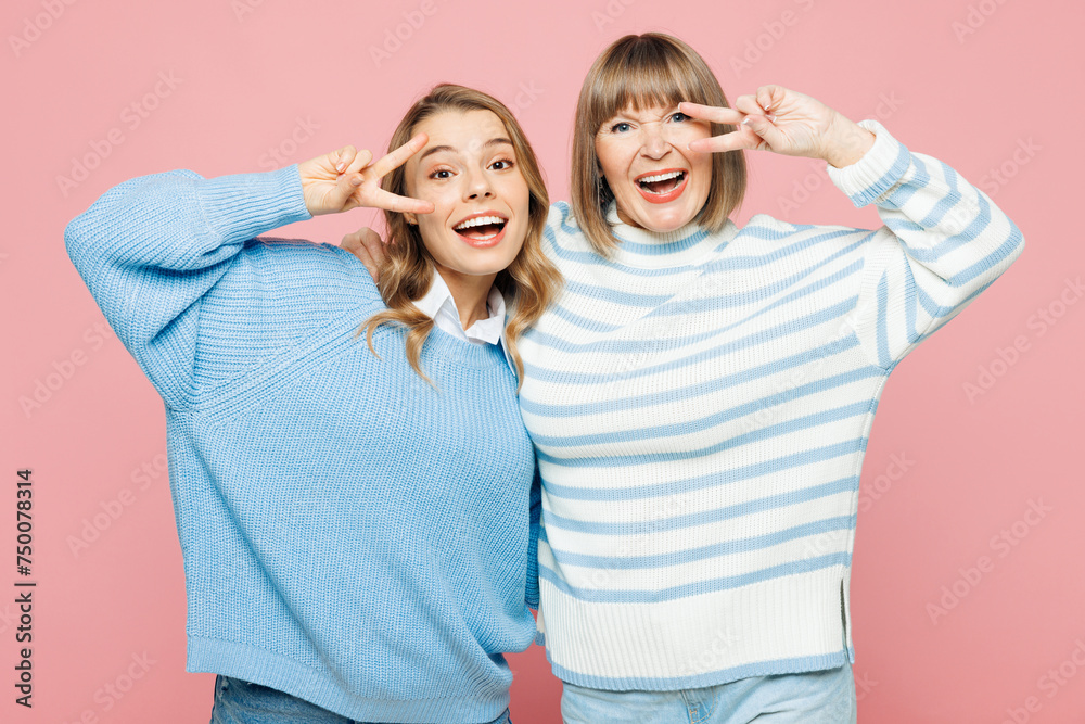 Elder smiling parent mom 50s years old with young adult daughter two women together wear blue casual clothes cover eyes with v-sign isolated on plain pastel light pink background. Family day concept. Elder smiling parent mom 50s years old with young adult daughter two women together wear blue casual clothes cover eyes with v-sign isolated on plain pastel light pink background. Family day concept.